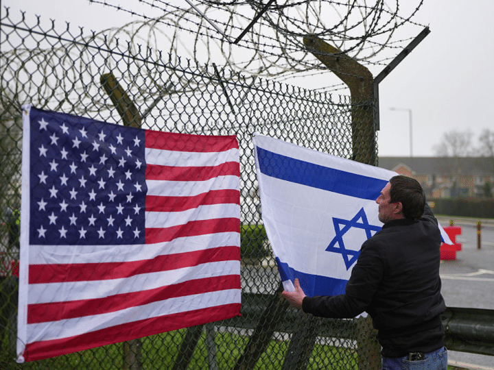 People who describe themselves as patriots display US and Israel flags as they set up their counter protest ahead of the protest by CND at RAF Fairford on March 7, 2026 in Fairford, England.