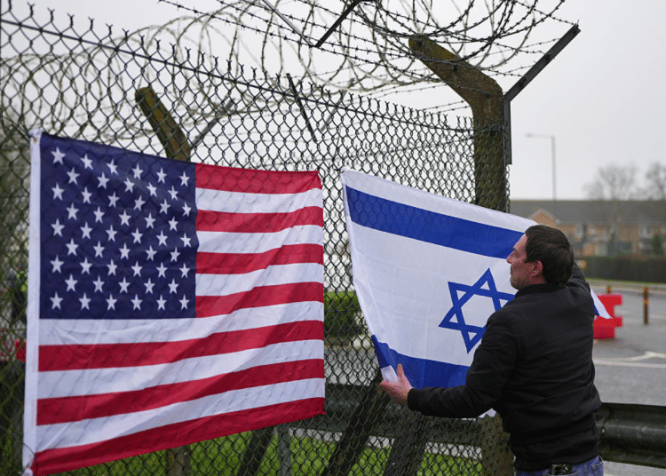 People who describe themselves as patriots display US and Israel flags as they set up their counter protest ahead of the protest by CND at RAF Fairford on March 7, 2026 in Fairford, England.