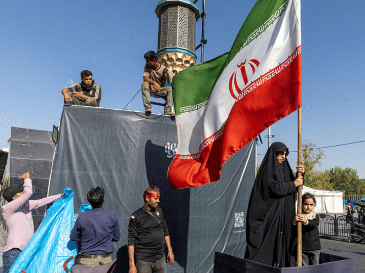 A woman is seen holding the Iranian Flag on June 15, 2026 in Tehran, Iran. According to reports, the U.S. and Iran have signed a preliminary agreement to end the war and open the Strait of Hormuz. The UAE is alleged to have agreed to unlock funds frozen in foreign banks under US sanctions for Iran.