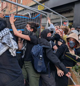 A group of masked people push back against a barricade