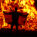 A male holds a flag in front of the Loyalist Corcrain Redmanville bonfire, which was lit to mark the start of the unionist 12 July celebrations, in Portadown, Northern Ireland, on 11 July 2021.
