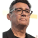 Head shot of Andy Burnham, wearing thick rimmed glasses, a crew neck tshirt and a blazer on top looking in the distance with quiet confidence. However, he has ruffled Scottish feathers.