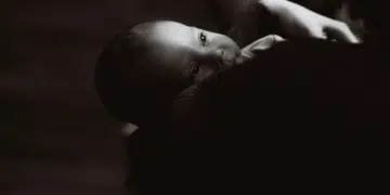 A black and white image of a newborn on someone's shoulder
