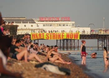 A banner hanging from Brighton pier reads Heat Strike Now as campaigners demand maximum working temperature
