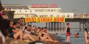 A banner hanging from Brighton pier reads Heat Strike Now as campaigners demand maximum working temperature