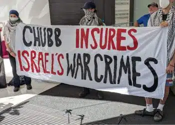Chubb lobby protesters lod a banner saying Chubb Insures Israel's War Crimes
