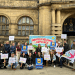 City of Sanctuary Sheffield supporters with their colourful 'Refugees Welcome Here'-type banners standing infront of what looks like a council building/ town hall