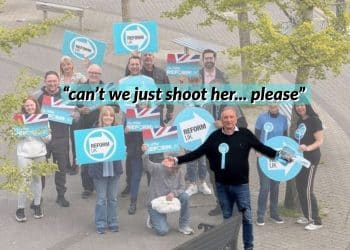 Reform UK politician Adrian White with others holding Reform logo posters behind him