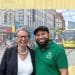 Geraldine Coggins and Mothin Ali of the Green Party smile next to one another in front of an image of a Manchester high street