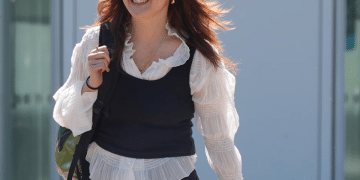 Ellie Kamio, one of the Filton 25, smiling while walking outside Woolwich Crown Court, London, in April 2026 with one hand on her shoulder keeping her backpack strap in place