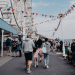 A bustling scene at Llandudno promenade in Wales with people walking near a Ferris wheel adorned with flags. Days out like this will not be affordable for many UK families due to money worries.