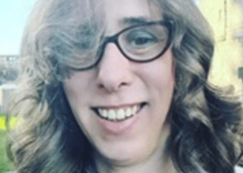 Close up selfie of Heather Herbert, who wears cat eye shaped glasses and has bouncy curls in her hair, and made mean comments online about Ann Widdecombe dying