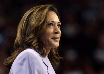 Kamala Harris smiling with a closed mouth in a smart suit looking into the distance, looking relaxed and assured