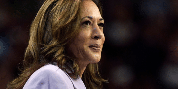 Kamala Harris smiling with a closed mouth in a smart suit looking into the distance, looking relaxed and assured