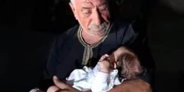 The grandfather of baby Lana Shahada, whose home was attacked by Israeli settlers, holds her and looks down at her