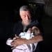 The grandfather of baby Lana Shahada, whose home was attacked by Israeli settlers, holds her and looks down at her