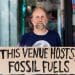 QEII fossil fuel protest Protester holds sign saying This Venue Hosts Fossil Fuels
