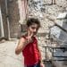 A young boy doing a victory sign in front of rubble in South Lebanon