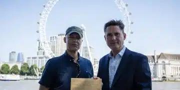 MPs Clive Lewis and Charlie Maynard in front of the Thames and London Eye, holding an open letter concerning Thames Water