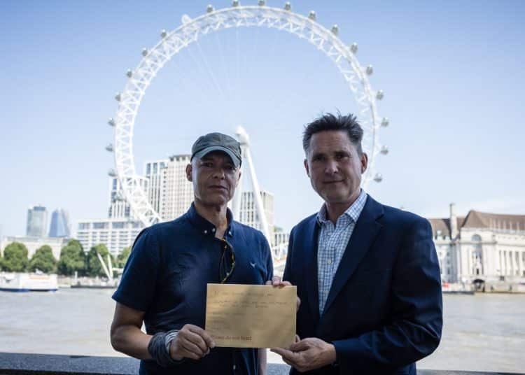 MPs Clive Lewis and Charlie Maynard in front of the Thames and London Eye, holding an open letter concerning Thames Water