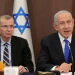 Yariv Levin (left) and Benjamin Netanyahu sat next to one another with mics infront of them and there is the star of Israel on decorations behind them