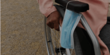 Close-up of the hand of a black woman pushing her wheelchair, she put her surgical face mask on the armrest. Police have warned unwell campaigners their health is not an automatic pass for wearing a face mask.